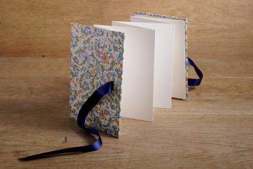 Standing leporello with light pages, book cover with colorful birds of paradise and ornaments, blue ribbon
